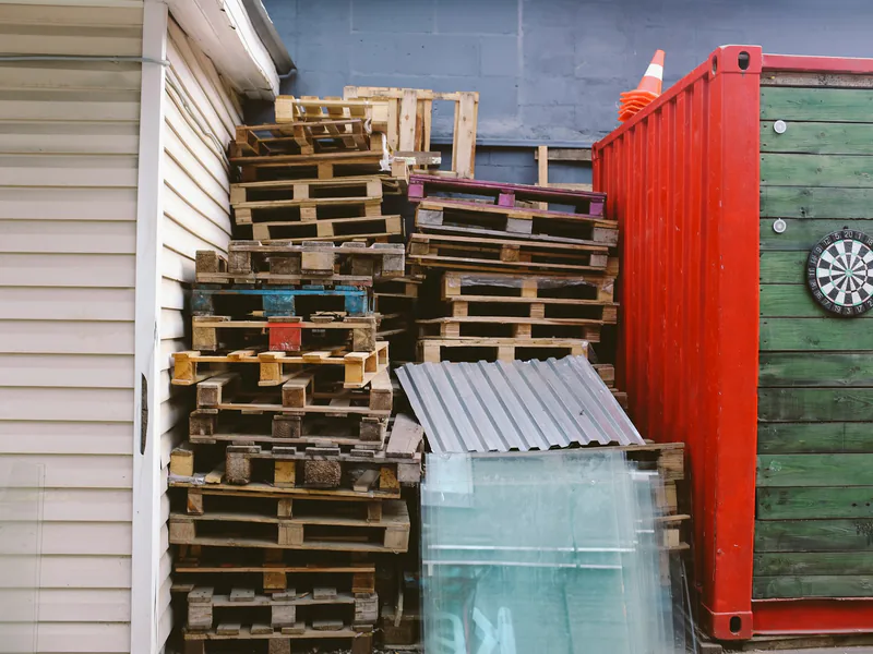 Wooden pallets stacked beside a shipping container